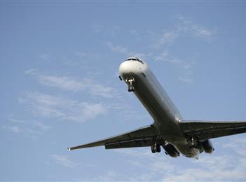 A large airplane flying in the sky with its landing gear down.